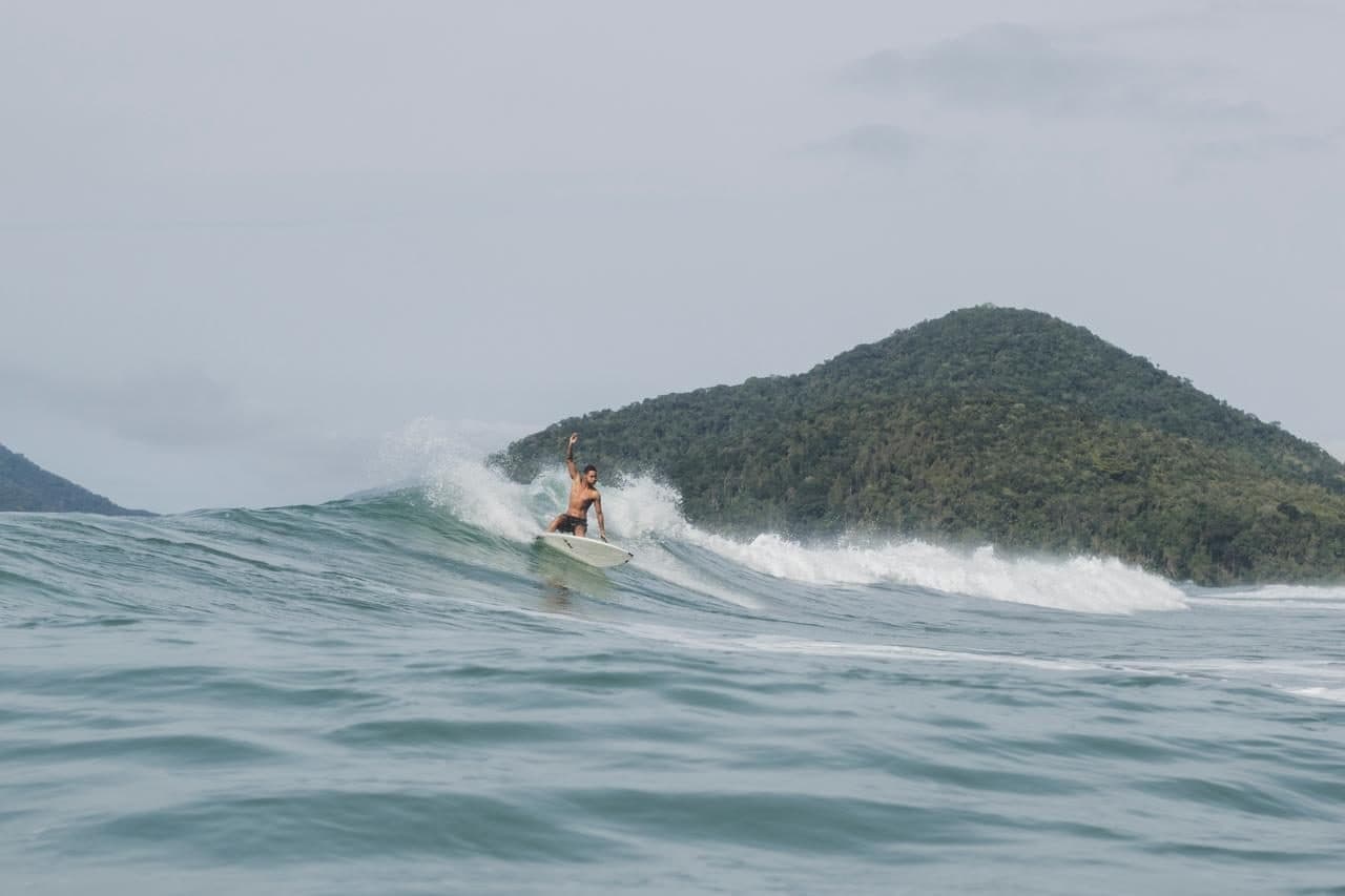 Surfista tomando una ola frente a la montaña